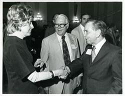 ["Black and white photograph print of Carl Albert shaking hands with an unidentified woman at his birthday party, 1976"]