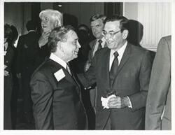 ["Black and white photograph print of Carl Albert speaking with Edward Boland at his birthday party, 1976 Thomas P. O'Neill is standing in the background, 1976"]