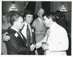 ["Black and white photograph print of Carl Albert speaking with Ray Harris and shaking hands with Robert E. Bauman at his birthday party, 1976"]