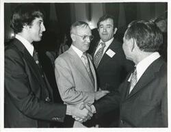 ["Black and white photograph print of Carl Albert at his birthday party shaking hands with an unidentified man. 1976"]