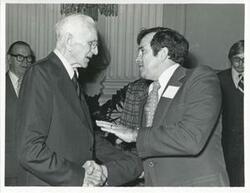 ["Black and white photograph print of John W. McCormack shaking hands with an unidentified man, 1976"]