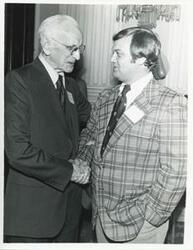 ["Black and white photograph print of John W. McCormack shaking hands with an unidentified man at Carl Albert's birthday party, 1976"]