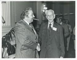 ["Black and white photograph print of John W. McCormack shaking hands with an unidentified man at Carl Albert's birthday party, 1976"]
