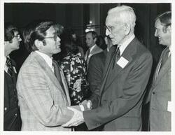 ["Black and white photograph print of John W. McCormack shaking hands with an unidentified man at Carl Albert's birthday party, 1976"]