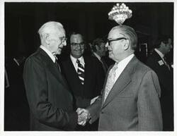 ["Black and white photograph print of John W. McCormack shaking hands with an unidentified man at Carl Albert's birthday party, 1976"]