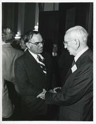 ["Black and white photograph print of John W. McCormack shaking hands with Congressman Joe Moakley from Massachusetts at Carl Albert's birthday party, 1976"]