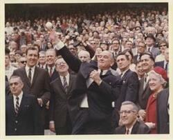 ["Black and white photograph print of John Pastore, Edmund Muskie, Lawrence F. O'Brien, Gerald R. Ford, John W. McCormack, Margaret Chase Smith, and Carl Albert. One of the men is throwing the ball out."]