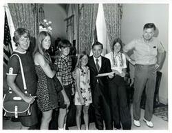 ["Black and white photograph print of Carl Albert posing with an unidentified family in his office."]