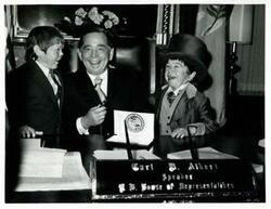["Black and white photograph print of Carl Albert seated at his desk with two midgets from the Ringling Bros. and Barnum and Bailey Circus."]