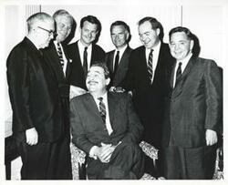 ["Black and white photograph print of Tom Steed, A. S. Mike Monroney, Jed Johnson, Jr., John Jarman, Ed Edmondson, and Carl Albert, standing behind Thomas Jefferson De Benning? who is seated."]