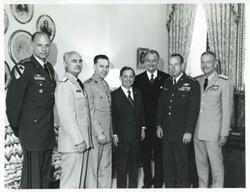 ["Black and white photograph print of Carl Albert posing with several military officers and Red Skelton"]