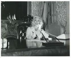 ["Black and white photograph print of Ginger Rogers talking on the phone in an office. October 2, 1975"]