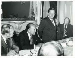 ["Black and white photograph print of Carl Albert, Gerald R. Ford, and two other men seated at a dinner table."]