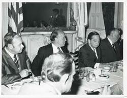 ["Black and white photograph print of Carl Albert, Gerald R. Ford, and two other men seated at a dinner table."]
