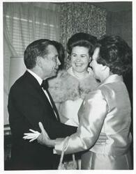 ["Black and white photograph print of Carl Albert speaking with two unidentified women."]