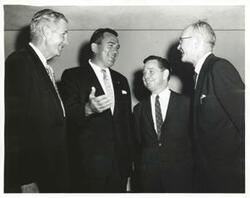 ["Black and white photograph print of Carl Albert, A. S. Mike Monroney, and two unidentified men speaking with one another."]