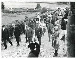 ["Black and white photograph print of Carl Albert and Mary Albert walking outside with several people. House delegation function. August 1975"]