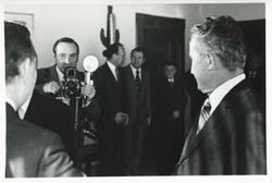 ["Black and white photograph print of a man taking a picture of Carl Albert and another man. House delegation trip. August 1975"]