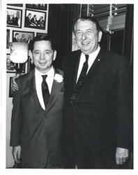 ["Black and white photograph print of Carl Albert posing with an unidentified man in an office."]