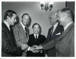 ["Black and white photograph print of Carl Albert joining hands with four other men."]