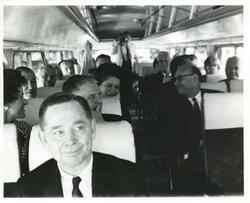 ["Black and white photograph print of Carl Albert and several others seated on a bus."]