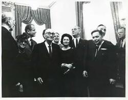 ["Black and white photograph print of Carl Albert, Carl Hayden, Lady Bird Johnson, Lyndon B. Johnson, Mike Mansfield, and others standing together."]