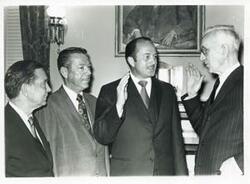 ["Black and white photograph print of Carl Albert speaking with three unidentified men."]