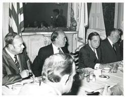 ["Black and white photograph print of Carl Albert speaking to men seated at a dinner table. Gerald R. Ford is present."]