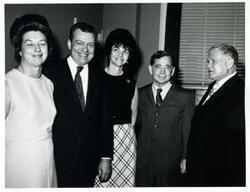 ["Black and white photograph print of Carl Albert standing with several unidentified people"]