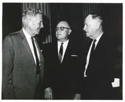 ["Black and white photograph print of A. S. Mike Monroney speaking with two unidentified men."]