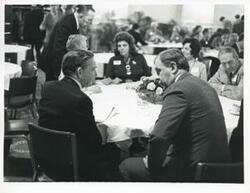 ["Black and white photograph print of Carl Albert speaking with an unidentified man at the reception for freshman members of the 94th Congress. December 1, 1975"]