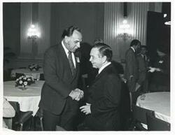 ["Black and white photograph print of Carl Albert shaking hands with an unidentified man at a reception for freshman members of the 94th Congress. December 1, 1975 Thomas P. O'Neill is present in 3077"]