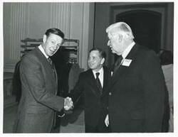 ["Black and white photograph print of Carl Albert shaking hands with an unidentified man at a reception for freshman members of the 94th Congress. December 1, 1975 Thomas P. O'Neill is present in 3077"]