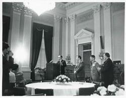 ["Black and white photograph print of Carl Albert speaking at a podium honoring freshman members of the 94th Congress. Another man is standing beside him. December 1, 1975"]