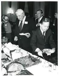 ["Black and white photograph print of Carl Albert and Thomas P. O'Neill going through a buffet line at a reception honoring freshman members of the 94th Congress. December 1, 1975"]