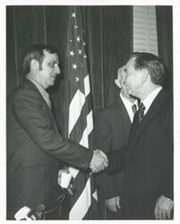 ["Black and white photograph print of Carl Albert shaking hands with an unidentified man."]