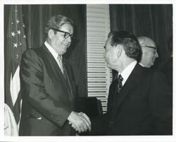 ["Black and white photograph print of Carl Albert shaking hands with Elliot Hogan."]