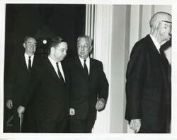["Black and white photograph print of Hubert H. Humphrey, Carl Albert, Charles O. Halleck, and Carl Hayden walking down a corridor."]