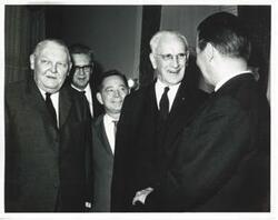 ["Black and white photograph print of Carl Albert, John W. McCormack, and others standing together."]