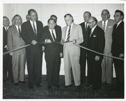 ["Black and white photograph print of John Brademas, Carl Albert, Michael Kirwan, and Hugh Carey at a ribbon cutting ceremony."]