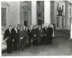 ["Black and white photograph print of Several unidentified men posing on the Capitol steps."]