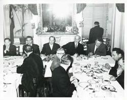 ["Black and white photograph print of Carl Albert, John W. McCormack, and others seated at dinner table."]