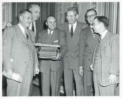 ["Black and white photograph print of Toby Morris, Robert S. Kerr, A. S. Mike Monroney, Carl Albert, and two other men standing together."]