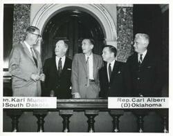 ["Black and white photograph print of Carl Albert standing with several unidentified men."]