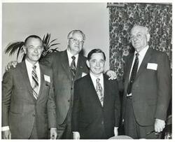 ["Black and white photograph print of Carl Albert posing with three unidentified men."]
