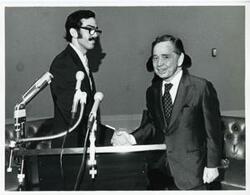 ["Black and white photograph print of Carl Albert shaking hands with an unidentified man."]