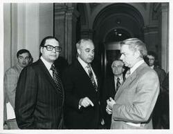 ["Black and white photograph print of Robert Strauss, Robert C. Byrd, and another man speaking to one another at a Democratic leadership conference."]