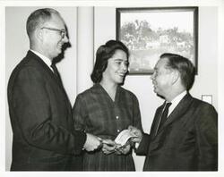 ["Black and white photograph print of Carl Albert presenting a House of Representatives check to Jean Bain. An unidentified man is also present."]