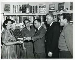 ["Black and white photograph print of Carl Albert with people from Wilson, Oklahoma, at the Wilson library."]