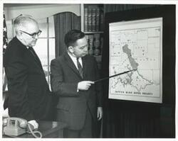 ["Black and white photograph print of photos A-C. Carl Albert with Tom Steed looking at a project map of the Upper Blue River Project."]